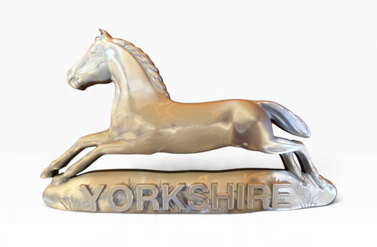 Close-up of the silver 3D-printed White Horse of Hanover above raised YORKSHIRE lettering on a white background