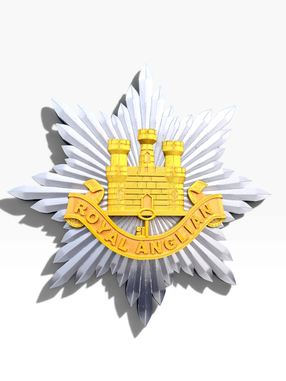 Royal Anglian Regiment cap badge display piece showing the finished regimental emblem and ROYAL ANGLIAN scroll
