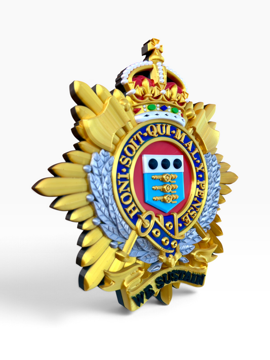 Royal Logistic Corps King's Crown cap badge viewed from the side, showing the thickness of the raised gold rays